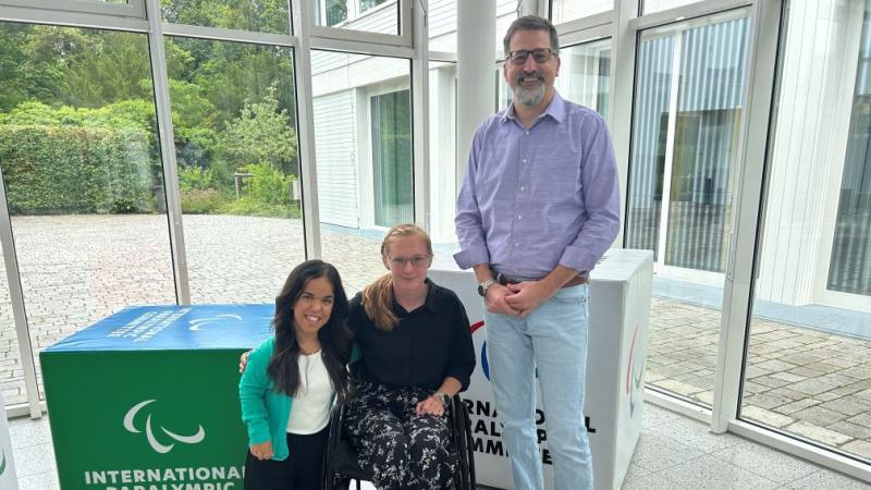 Two female Para athletes and IPC CEO Mike Peters pose for a photo at the IPC headquarters