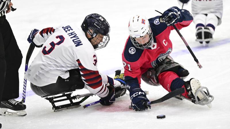 A Norwegian and a Korean Para ice hockey player going for the puck