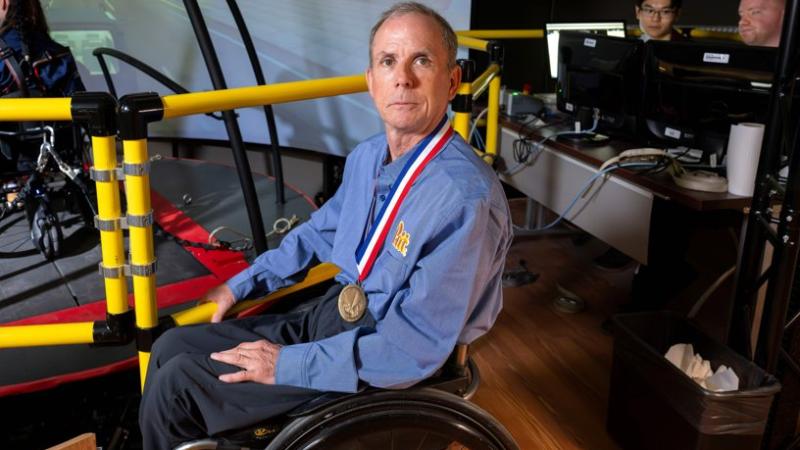 Rory Cooper sitting in a wheelchair with a medal around his neck