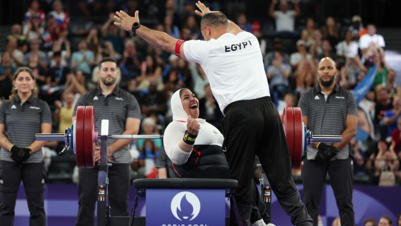 A female Egyptian Para powerlifter celebrates with her coach after her lift at Paris 2024
