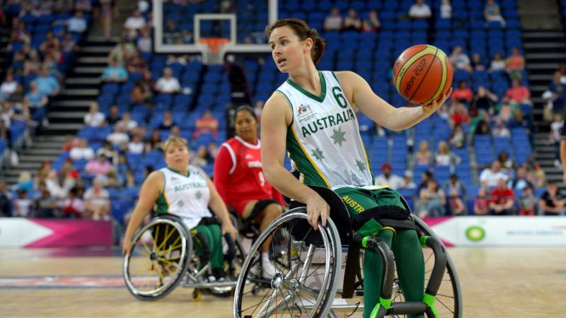 A female wheelchair basketball player is dribbling the ball during a game
