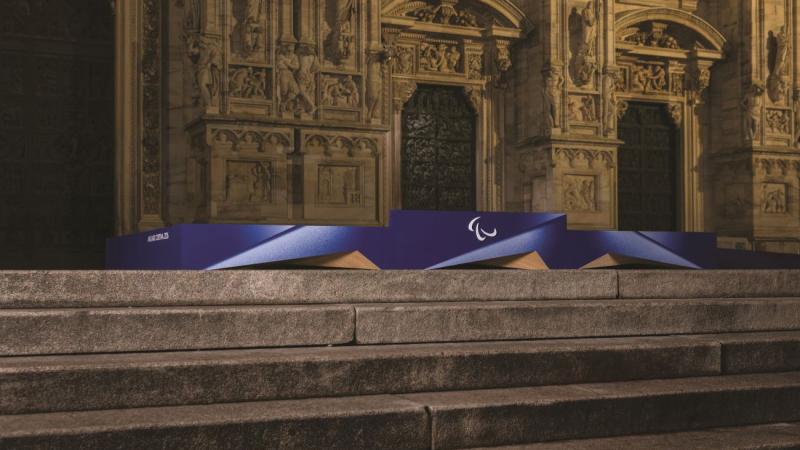 A purple podium with the Agitos logo in the centre is placed in front of a historic building