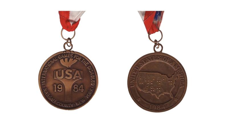 The front and back side of the New York 1984 Paralympic games medal.