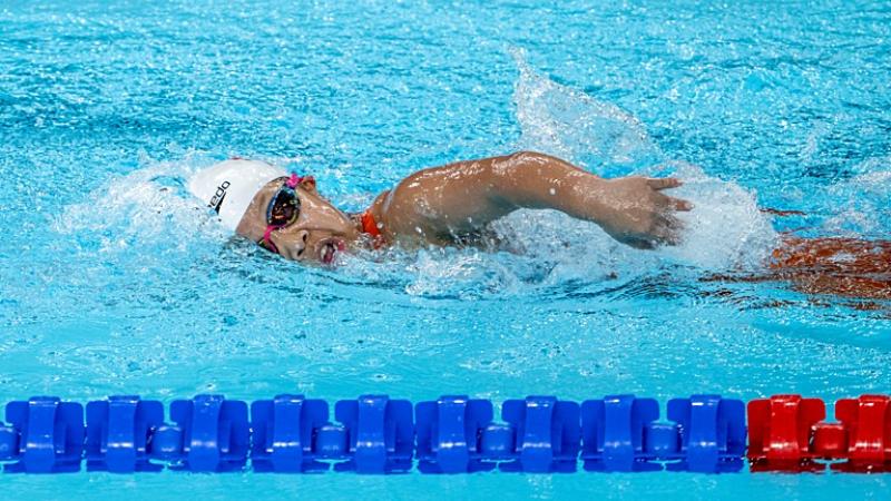 A female Para swimming athlete is competing in a freestyle event