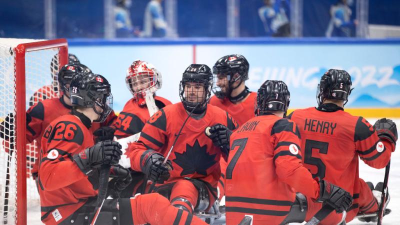A group of Canadian Para ice hockey players gathering on the rink