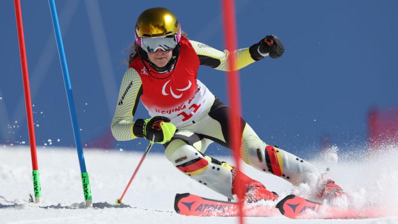 A female athlete skiing downhill between poles