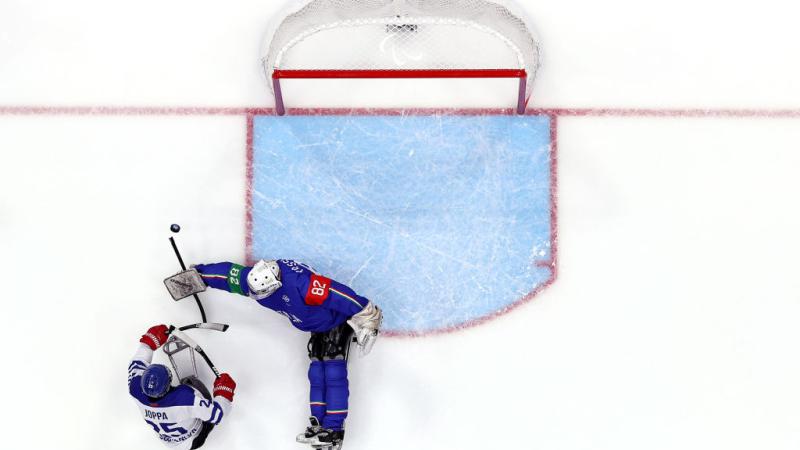 An aerial view of a Para ice hockey player scoring in front of a goaltender
