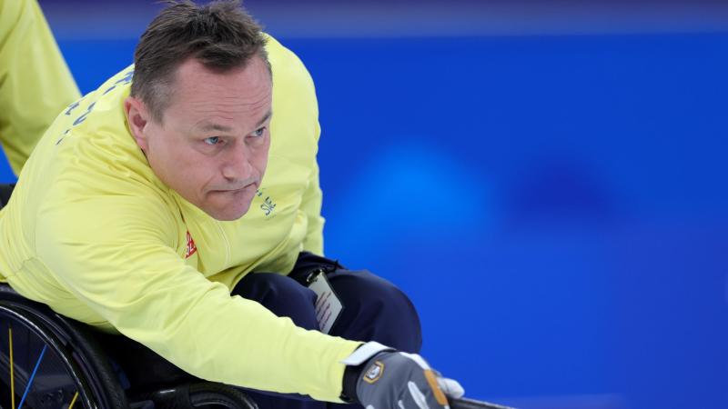 A male wheelchair curler releasing the stone with the stick