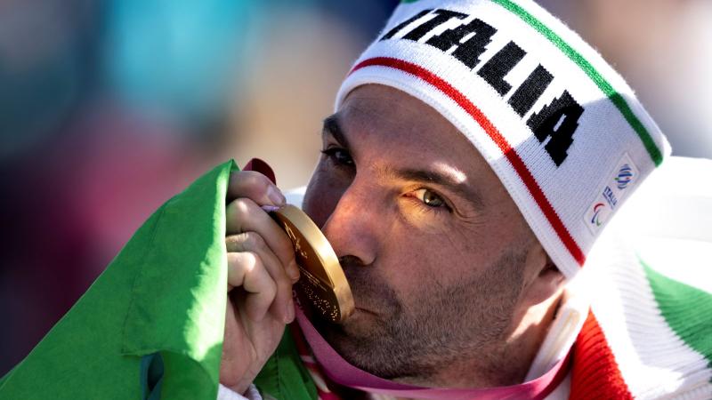 A male athlete is kissing his Paralympic gold medal