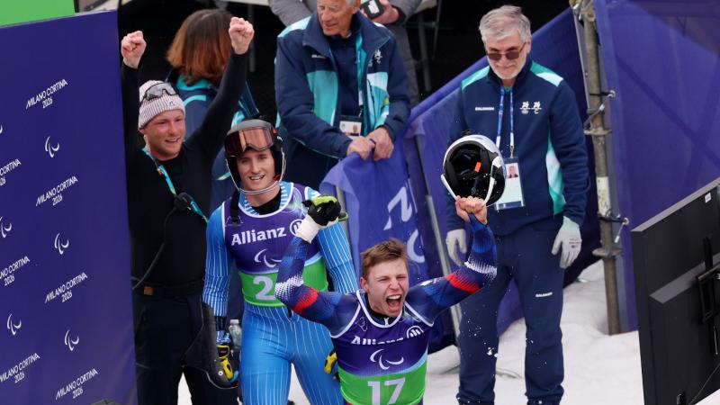 A male athlete is celebrating in front of athletes and volunteers