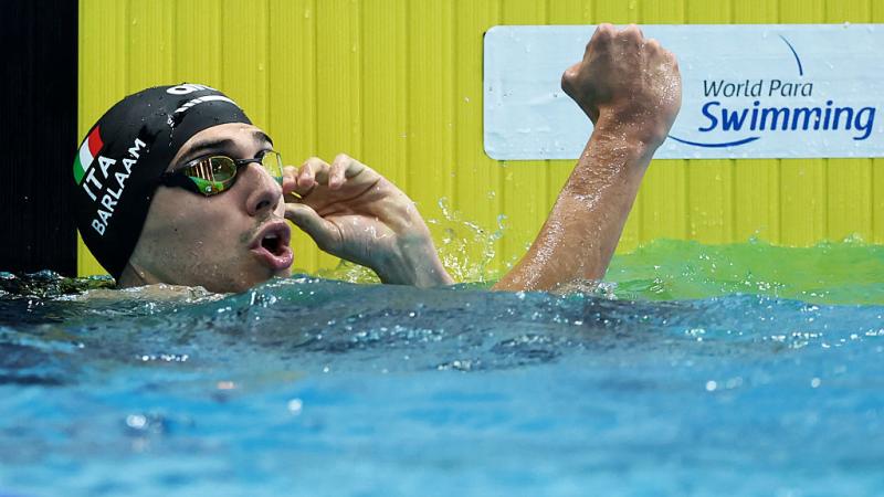 A male athlete celebrating from the pool next to the World Para Swimming logo