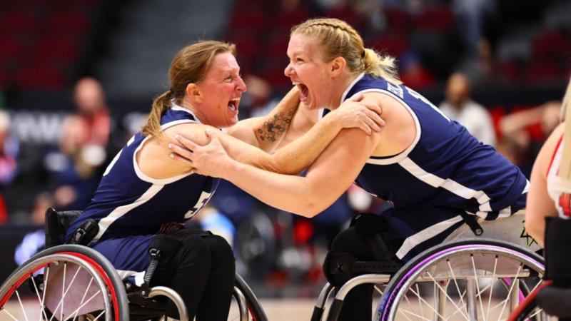 two female wheelchair basketball players from the USA scream and hug in celebration 