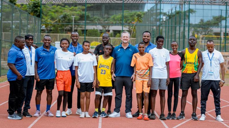 Fifteen people are posing for a photograph on a track