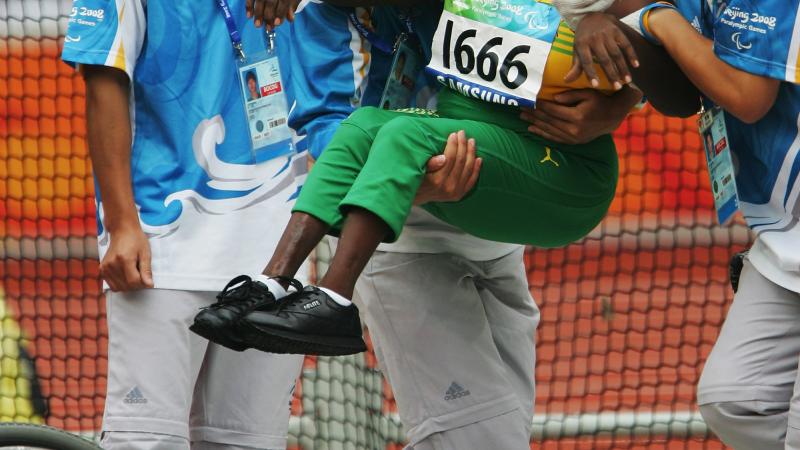 Jamaican athlete being transferred to her wheelchair during the 2008 Beijing Games