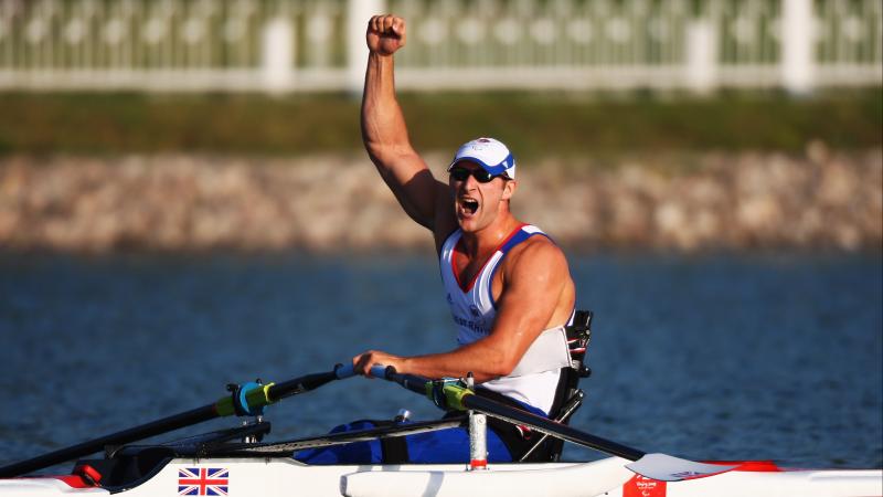 British male rower holds fist in air in celebration