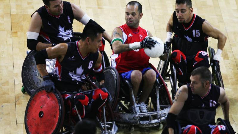 A picture of a person in a wheelchair trying to make a pass between four other person in a wheelchair.