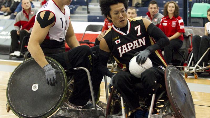 A picture of man in a wheelchair resisting to a choch with another wheelchair.