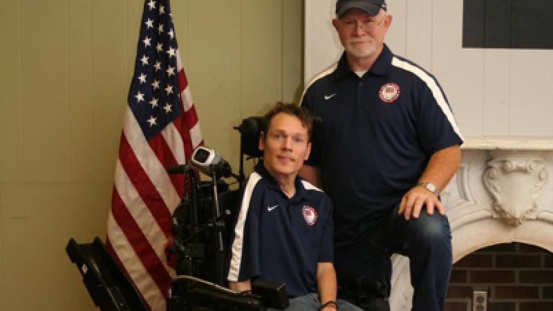 A picture of a man in an electric wheelchair posing for a picture with another man