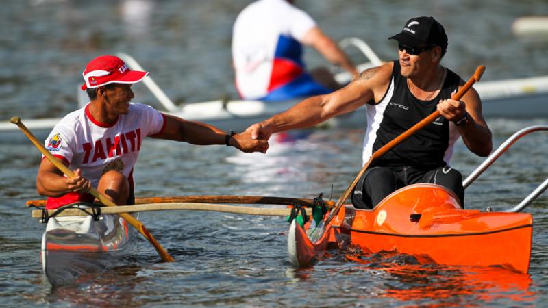 A picture of 2 men in a canoe shaking their hands celebrating a victory