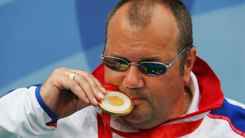 A picture of a man kissing his gold medal