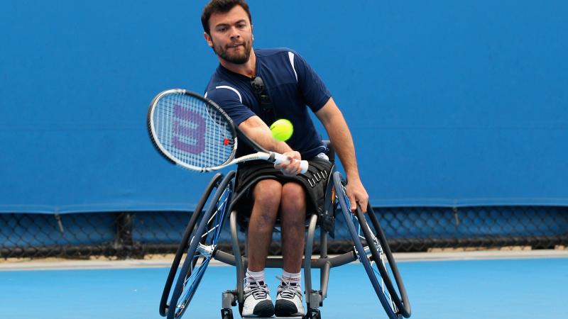 A picture of a man in a wheelchair playing tennis.