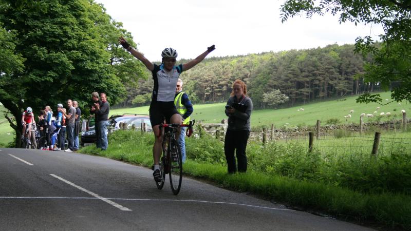 A picture of a woman on a cycle celebrating her victory