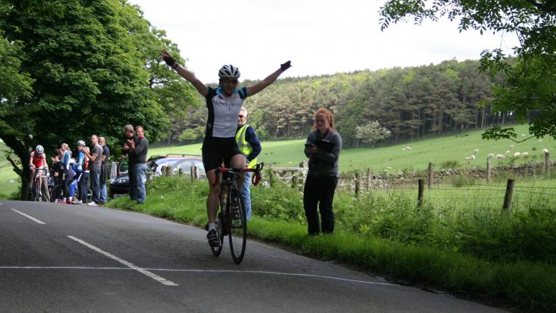 A picture of a woman on a cycle celebrating her victory