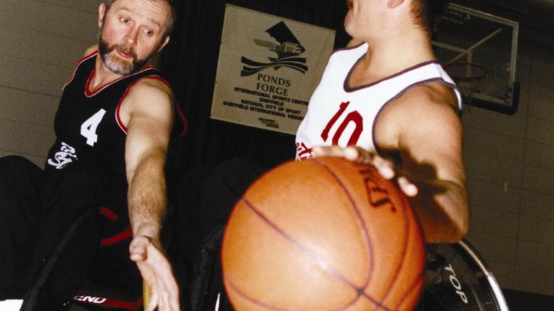 A picture of 2 men in a wheelchair playing basketball