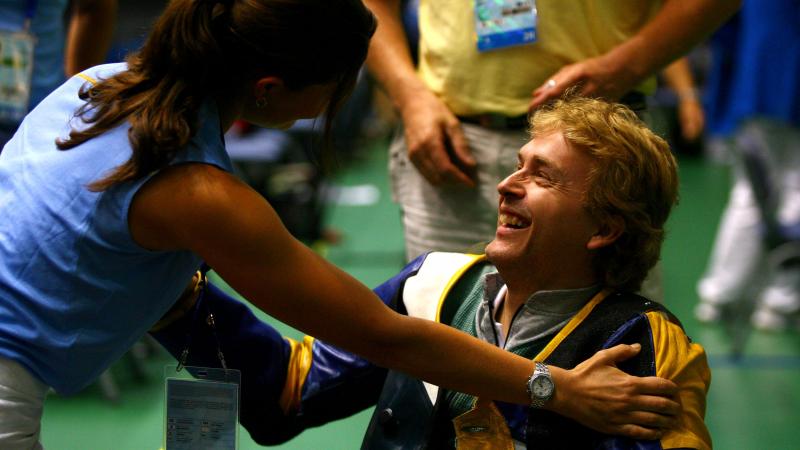 A picture of a man in a wheelchair congratulated by a woman