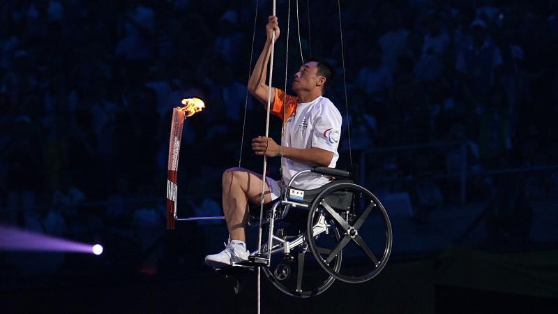 A picture of a man in wheelchair climbing with a torch