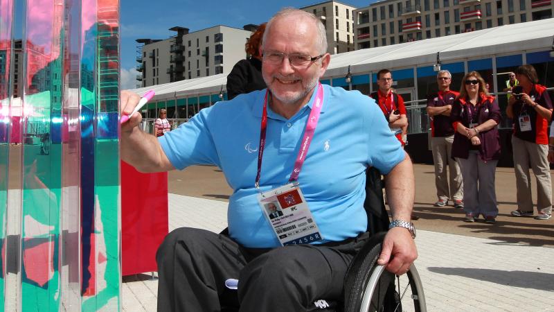 A picture of a man in a wheelchair signing a wall