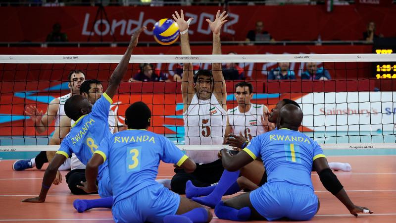 A picture of mens sit down on the ground and playing volleyball.