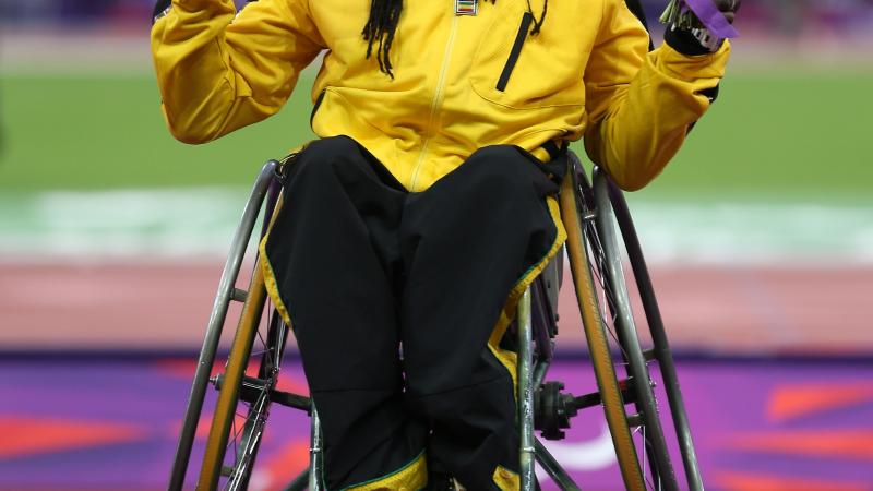 A picture of a man in a wheelchair showing his gold medal