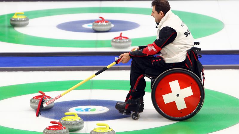 A picture of a man in a wheelchair playing Curling