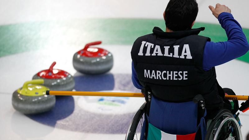 A picture of a man in a wheelchair playing curling.