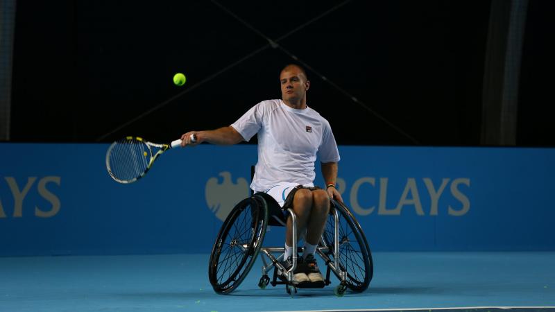 A picture of a man in a wheelchair playing tennis.