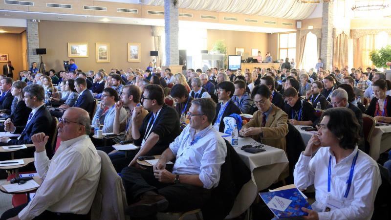 A picture of room fill in by several attendees listening a conference