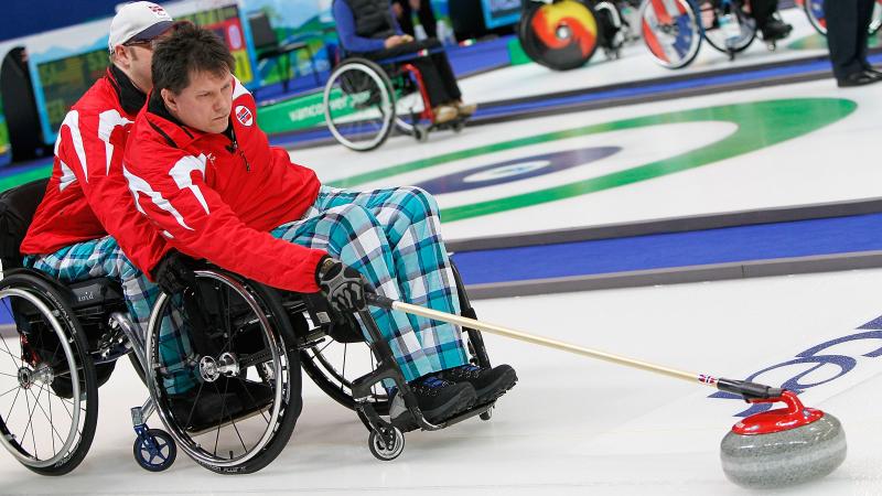 A picture of a man in a wheelchair playing curling