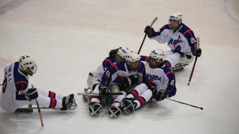 A picture of men sitting in a sledge celebrating their victory in a hockey match.