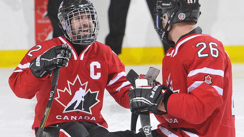 A picture of a man in sledge celebrating his victory in ice hockey match