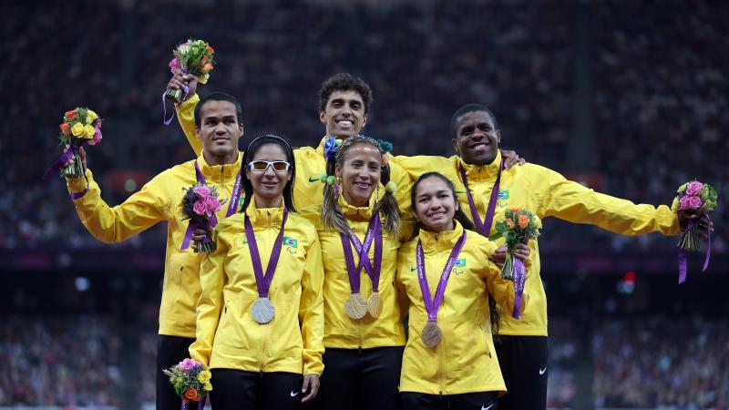 A picture of six person on a podium showing their medals