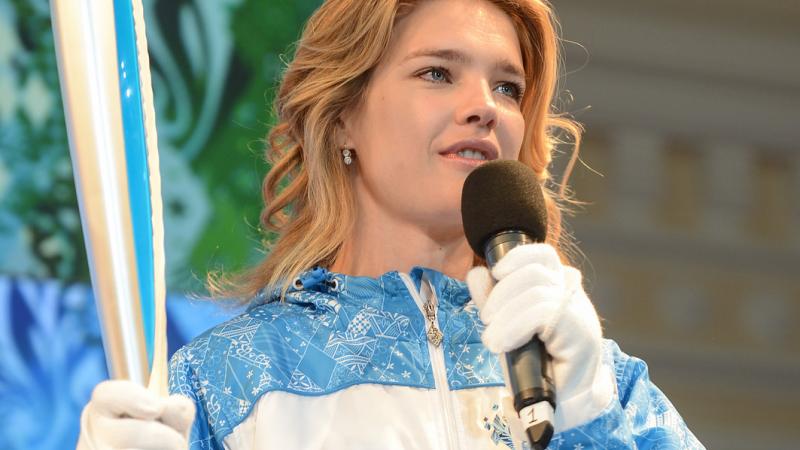 A picture of a woman holding a torch and speaking on a microphone.