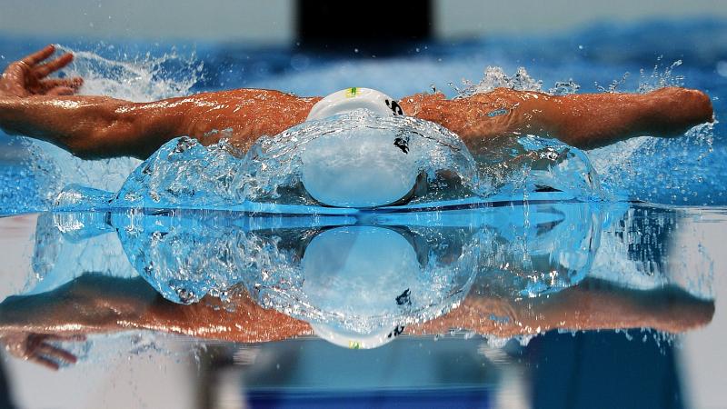 A picture of a man swimming with his both hands above the surface