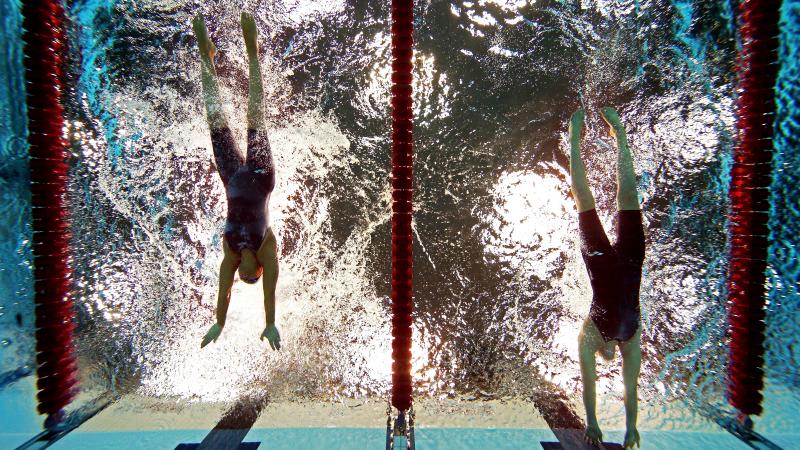 A picture of women in the pool touching the wall with their hands