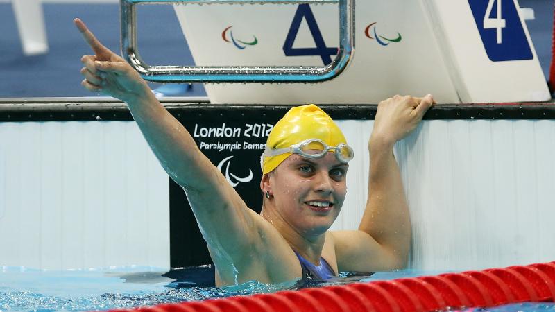 A picture of a woman in the pool holding her hand up