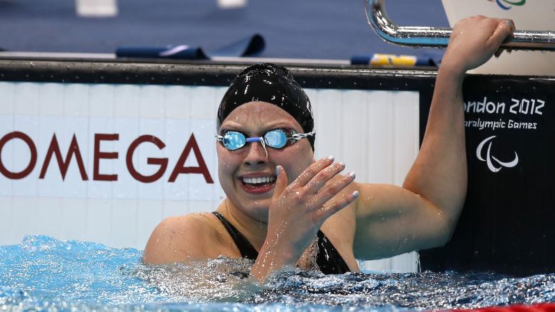 A picture of a woman in the pool holding the starting block with her hand