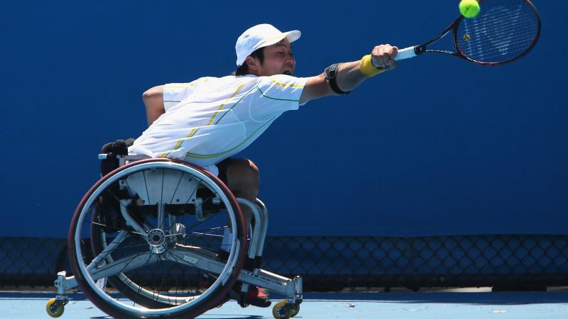 A picture of a man in a wheelchair playing a backhand during a wheelchair tennis match