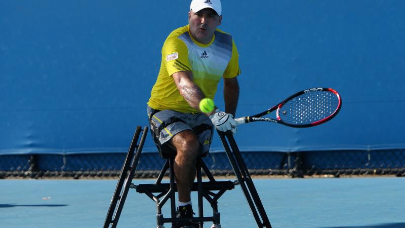 A picture of a man in a wheelchair playing a backhand during a wheelchair tennis match