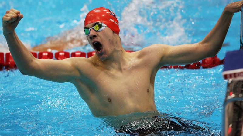 A picture of a man in the pool holding his hand up with clenched fist