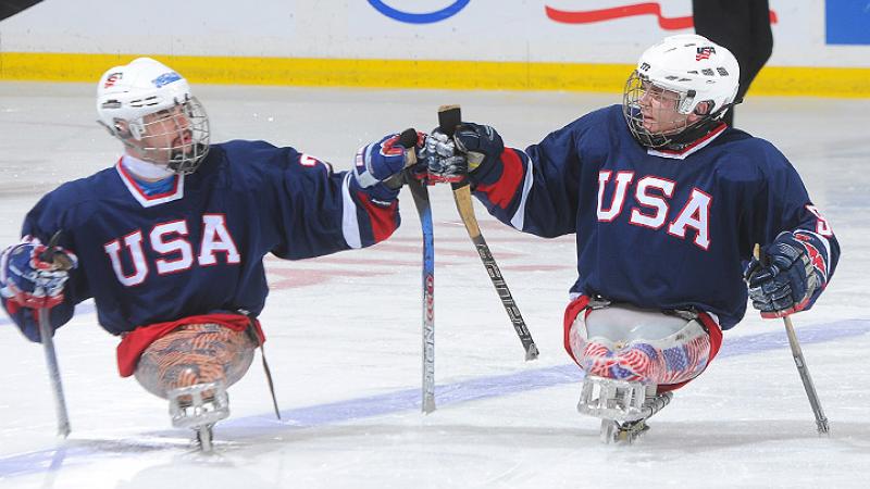 A picture of 2 mens in sledges during an ice sledge hockey match